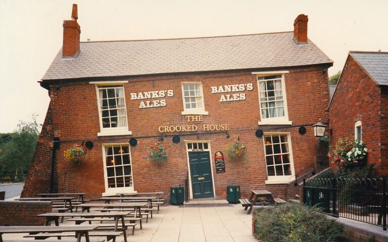 Photo of the Crooked House, a brick-built pub leaning to the left and supported by large buttresses